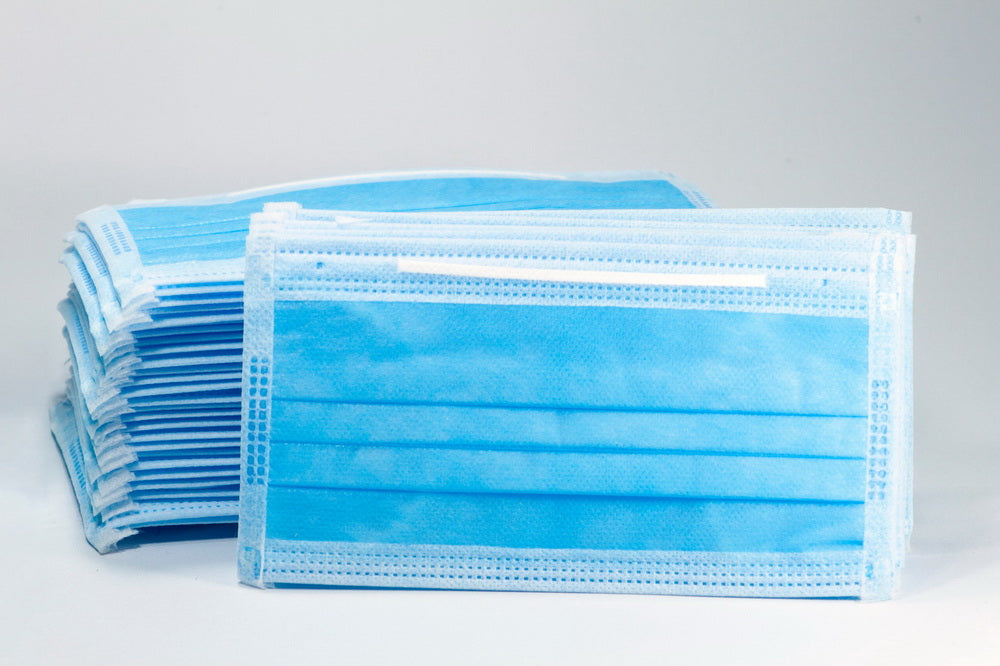 Stack of blue disposable 3-ply face masks